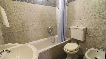 Un baño con bañera, inodoro, bidé y lavabo.