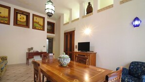 A dining area with a wooden table, chairs, a TV, and decorative items on the walls. - Beautiful private villa for 4 people with A/C, WIFI, TV and panoramic view (Otranto)