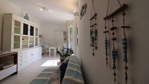 Ein helles Wohnzimmer mit einer Couch, einem weißen Schrank und einer hängenden Fischdekoration.