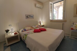 Een slaapkamer met een bed, nachtkastje, raam en radiator.