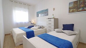 Una camera da letto con due letti, un comodino, una cassettiera e un quadro appeso al muro.
