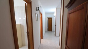 A hallway with wooden doors, white tiled flooring, and a framed picture on the wall. - Wonderful  villa for 8 guests with A/C, WIFI, TV and balcony (Otranto)