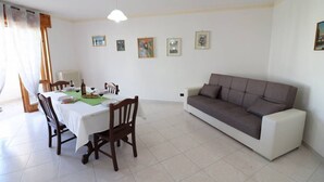 A dining area with a table set for two, a sofa, and a radiator. - Wonderful  villa for 8 guests with A/C, WIFI, TV and balcony (Otranto)
