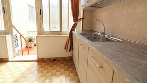 Una cocina con lavamanos, armarios y ventana con cortinas.