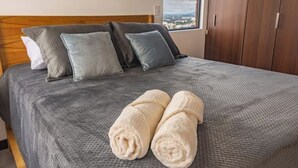 A neatly made bed with a grey textured bedspread, two rolled white towels, and a wooden headboard. - *Comfortable apartment* minutes away from cayala (Ciudad de Guatemala)