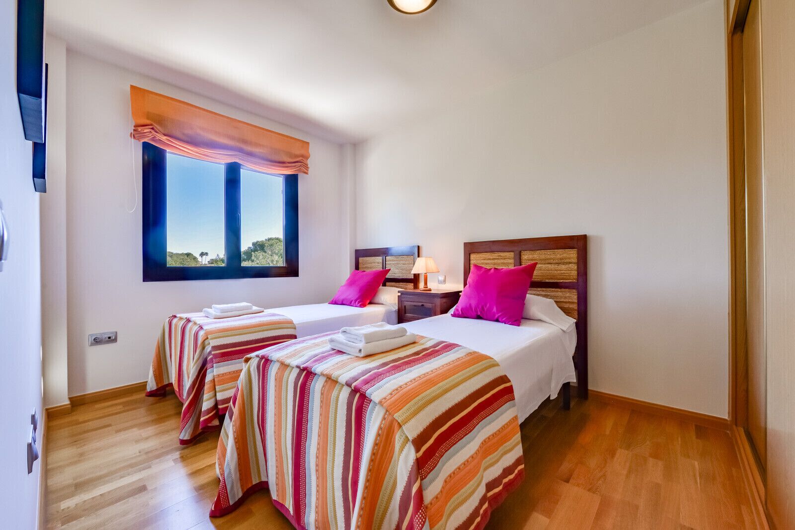 A hotel room with two beds, a window with a view, and a wooden floor.