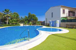 Une piscine à bord incurvé, entourée d’une pelouse bien entretenue et de palmiers.