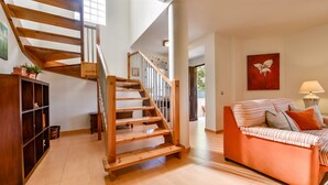 A spacious living area with a wooden staircase, a sofa with striped cushions, and a painting on the wall. - Rental in Calpe REAL SITIO (Calpe)