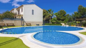 A swimming pool with a circular design, surrounded by a well-maintained lawn and a building with a balcony. - Rental in Calpe REAL SITIO (Calpe)