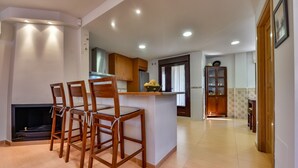 A modern kitchen with wooden chairs, a central island, and a built-in stove. - Rental in Calpe REAL SITIO (Calpe)