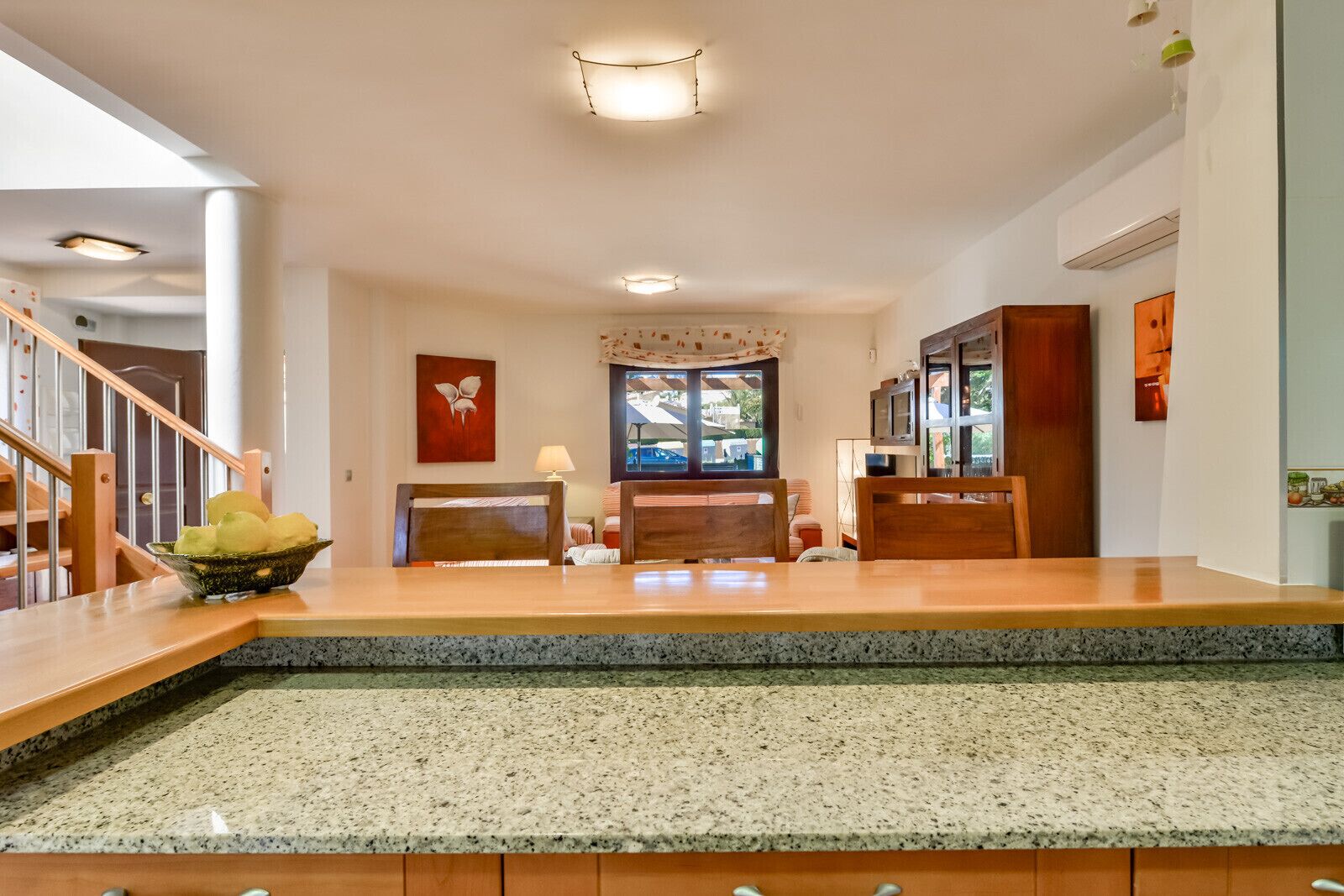 A spacious living area with a wooden dining table, a comfortable sofa, and a kitchen area with granite countertops.