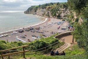 Ein Küstenstrand mit Booten, einer Holztreppe und einer Bank.