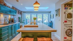 Une cuisine moderne dotée d’un îlot central, d’appareils électroménagers intégrés et offrant une vue dégagée grâce à de grandes fenêtres.