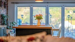 Une cuisine moderne avec une grande fenêtre, un vase rempli de fleurs et un plan de travail en bois.