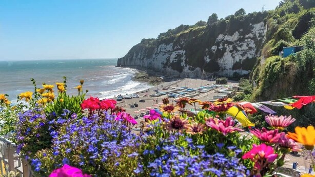Une vue côtière avec une plage, des bateaux et des falaises.