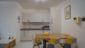 Une cuisine moderne avec des meubles blancs, une table à manger en bois et deux chaises à motifs à carreaux.