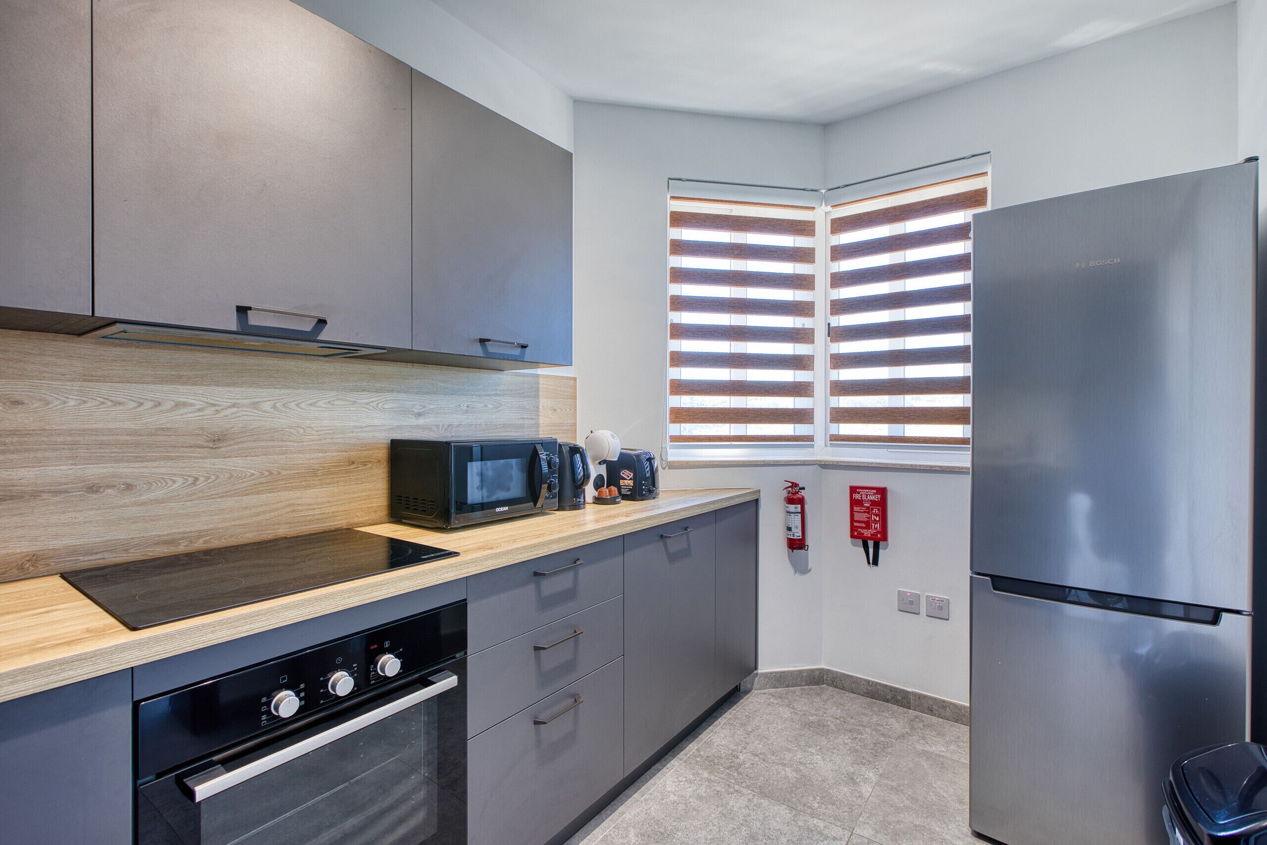 A modern kitchen with a built-in oven, microwave, and coffee maker.