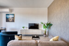 A modern living room with a flat-screen TV, a sofa, a coffee table, and a potted plant. - Modern Maisonette with Valley Views KARP1-3 (San Gwann)