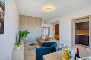 Een moderne woonkamer met een bank, een eettafel met wijnflessen, en een keuken op de achtergrond.