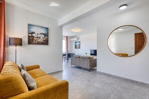 Een moderne woonkamer met een bank, een ronde spiegel en een schilderij aan de muur.