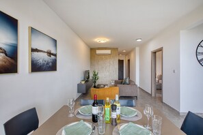 A dining area with a table set for four, a sofa, and a clock on the wall. - Modern 2 bedroom apartment, Valley Views KARP1-4 (San Gwann)