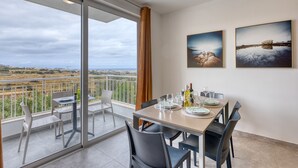 Ein Essbereich mit Tisch für vier Personen, ein Balkon mit Aussicht und zwei gerahmte Bilder an der Wand.