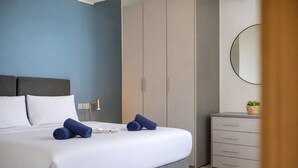 Ein modernes Schlafzimmer mit Bett, Nachttischlampe, Kleiderschrank und Kommode.
