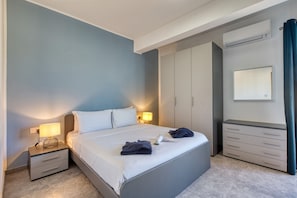 A modern bedroom with a bed, bedside tables, a wardrobe, and an air conditioning unit. - Central and modern Apartment, Valley Views KARP1-6 (San Gwann)