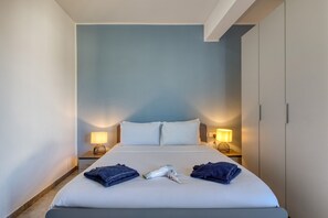 A neatly made bed with pillows, two bedside lamps, and towels on the bed. - Central and modern Apartment, Valley Views KARP1-6 (San Gwann)