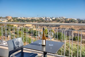 A balcony with a table, a bottle of wine, and two glasses. - Central and modern Apartment, Valley Views KARP1-6 (San Gwann)