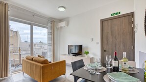 Un soggiorno moderno con divano, tavolo da pranzo per due persone e televisione.