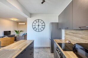 A modern kitchen with a large wall clock, built-in appliances, and a wooden countertop. - 2 bedroom flat with balcony, valley views KARP1-8 (San Gwann)