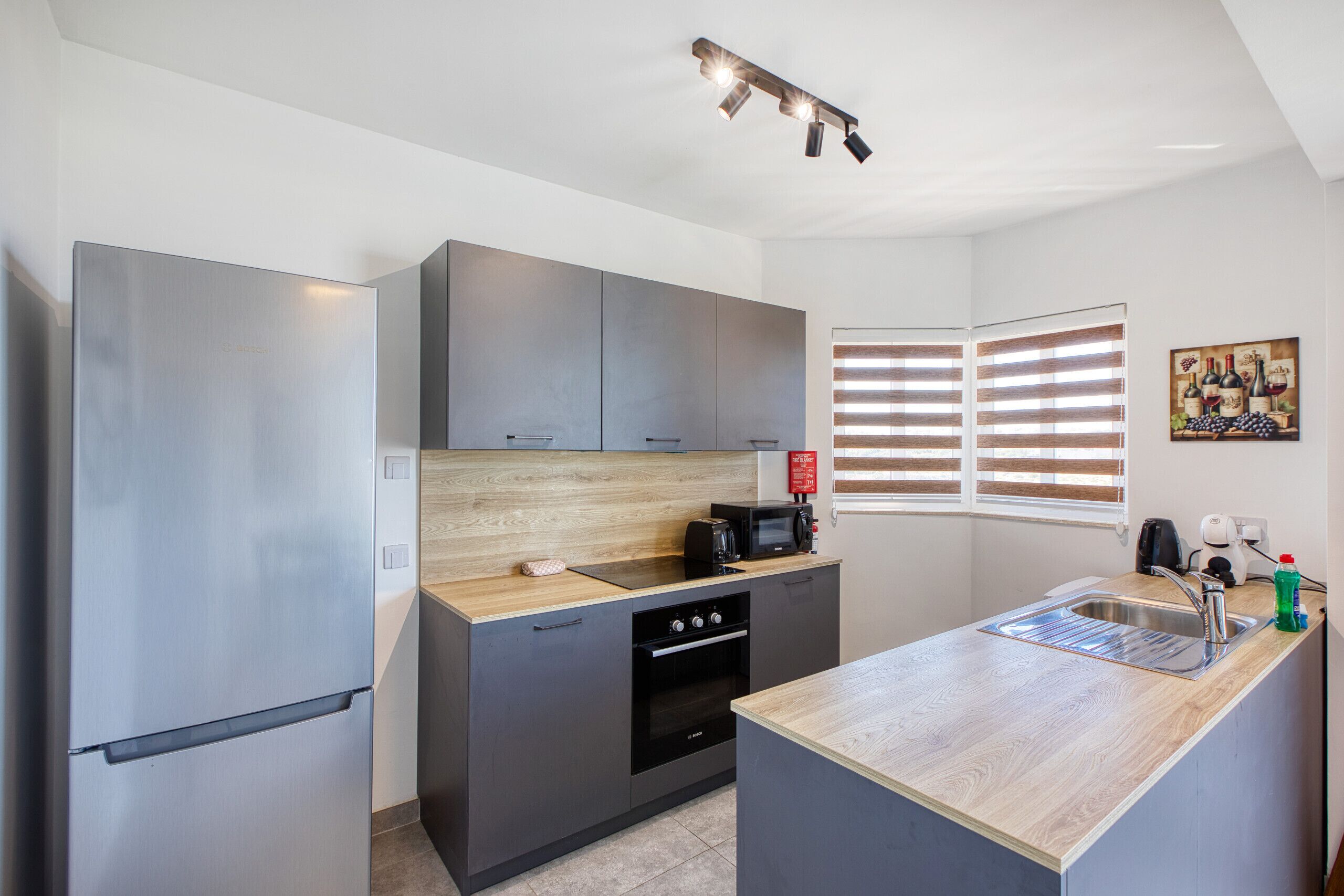 A compact kitchen with a refrigerator, stove, microwave, and sink.