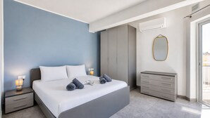 A modern bedroom with a bed, bedside tables, a wardrobe, and an air conditioning unit.