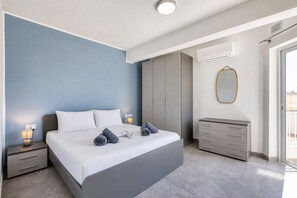A modern bedroom with a bed, bedside tables, a wardrobe, and an air conditioning unit. - 2 bedroom flat with balcony, valley views KARP1-8 (San Gwann)