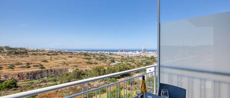 A balcony with a table, two wine glasses, and a bottle.