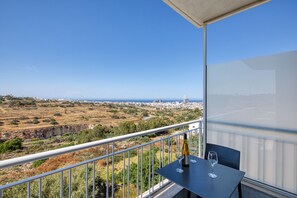 A balcony with a table, two wine glasses, and a bottle. - 2 bedroom flat with balcony, valley views KARP1-8 (San Gwann)