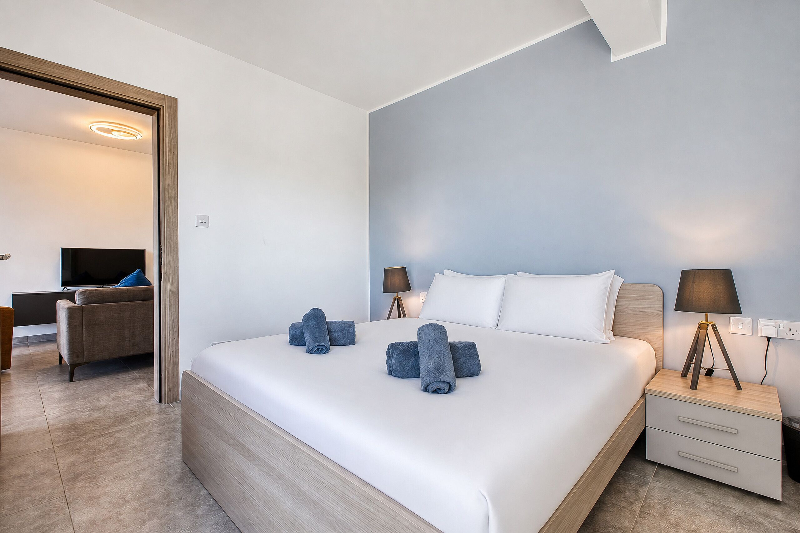 Una habitación de hotel con una cama grande, dos mesitas de noche con lámparas, un televisor y un sofá.