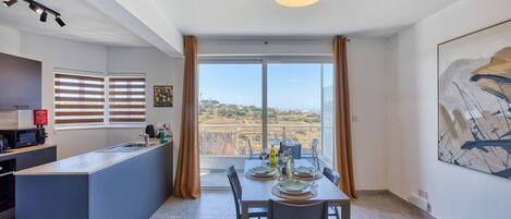 Una cocina moderna con comedor, un amplio ventanal con cortinas y vistas al paisaje.