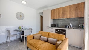 Eine moderne Küche mit Holzausstattung, ein Essbereich mit Tisch und Stühlen sowie eine Sitzecke mit Sofa.