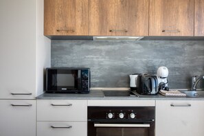 A kitchen with wooden cabinets, a microwave, a toaster, and an oven. - Refined 2 bedroom apartment with balcony KARP1-9 (San Gwann)