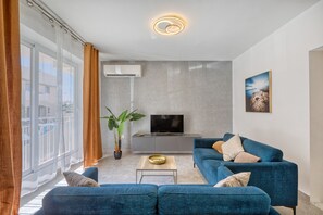Ein modernes Wohnzimmer mit einer Couch, einem Couchtisch, einem Fernseher und einer Pflanze.