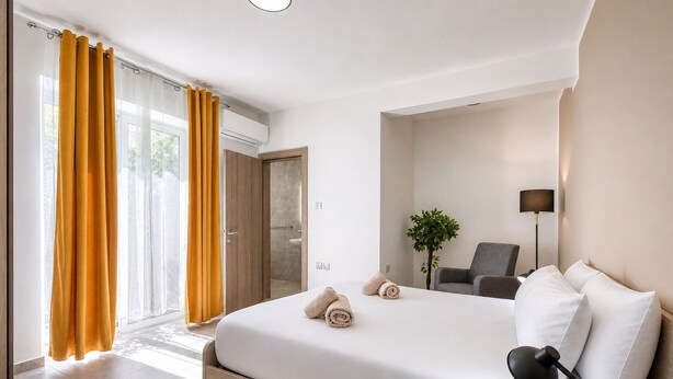Una camera d'albergo con un letto, una scrivania, una sedia, una lampada e una pianta.