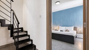 Una camera da letto moderna con un letto, un comodino e una scala con ringhiere nere.