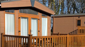 A wooden cabin with a balcony and large windows.