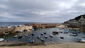 A coastal harbor with boats, a stone pier, and a town in the background.