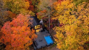 Ein Haus mit Terrasse und Pool, umgeben von Herbstlaub.