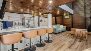 Eine moderne Küche mit einer zentralen Kochinsel, Barhocker und einem Essbereich mit Holztisch und Stühlen.