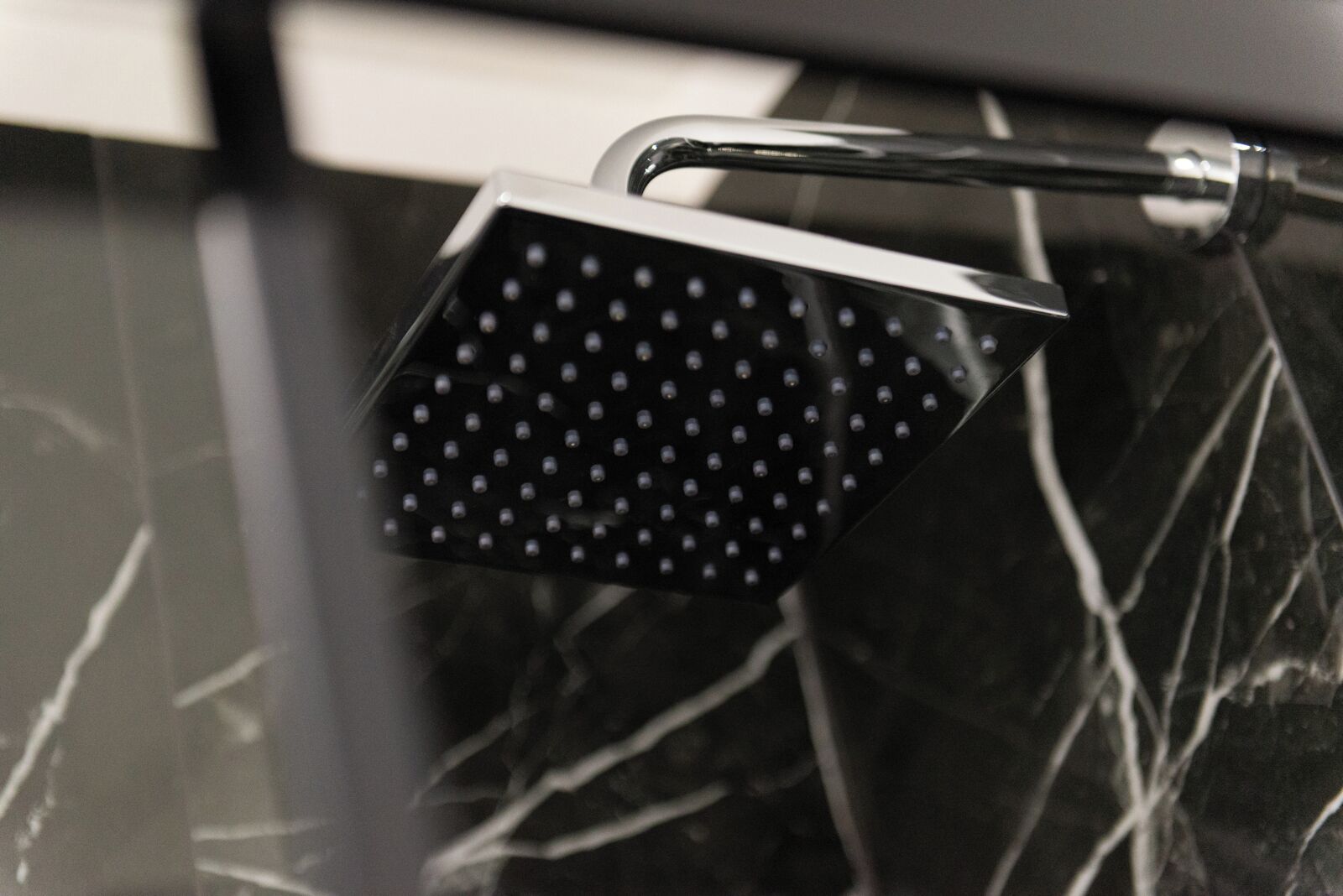 A showerhead with a square design and multiple small holes.