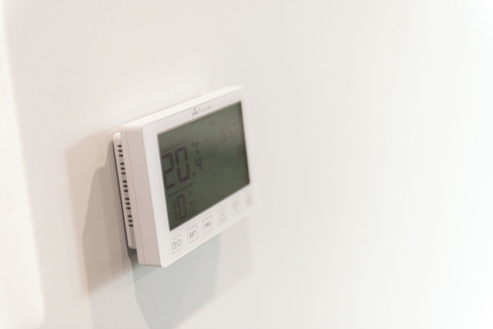 Termostato digital montado en una pared blanca.